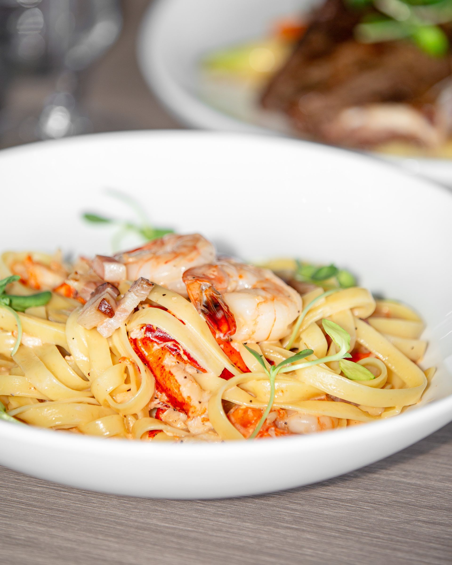 A white bowl filled with noodles and shrimp on a table.