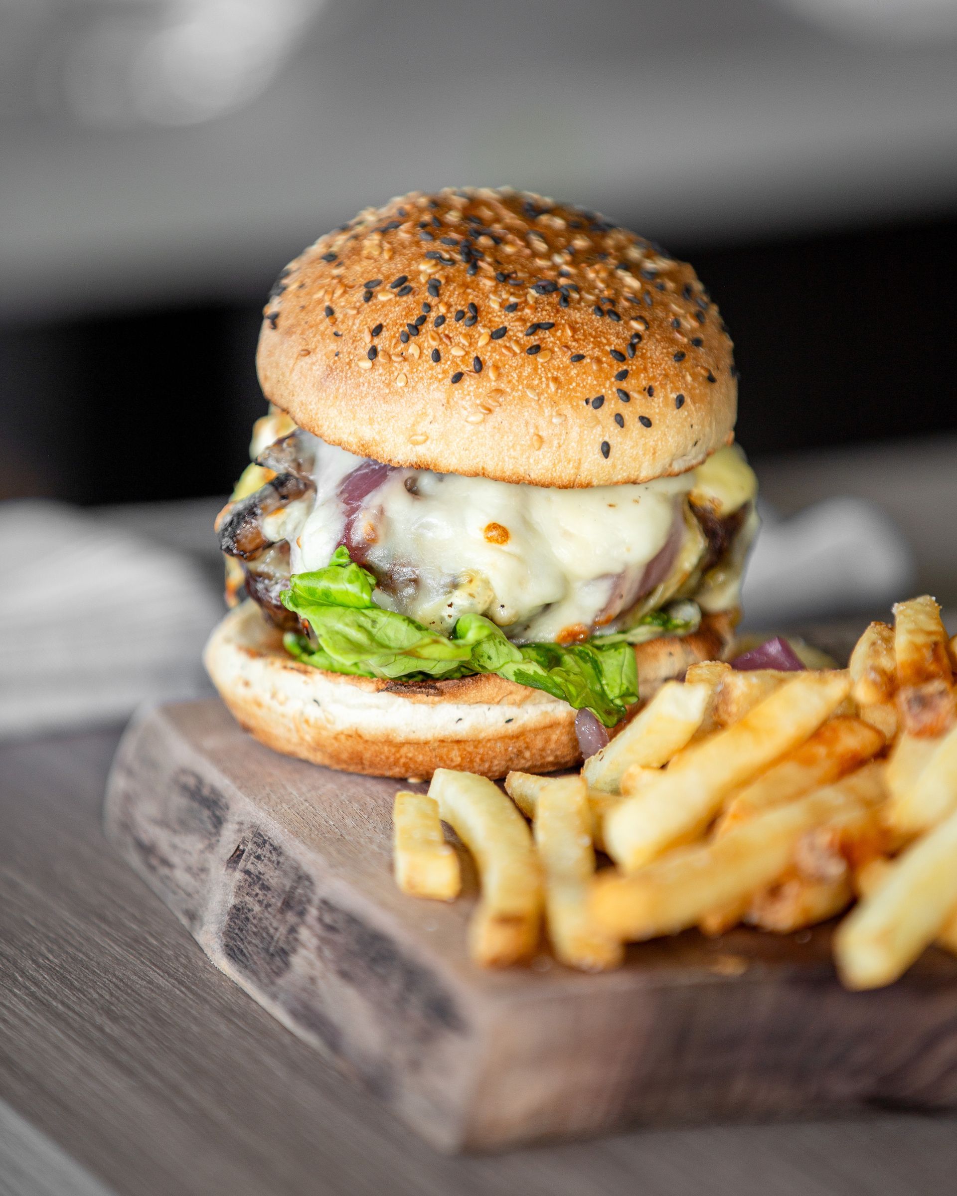 A hamburger and french fries are on a wooden cutting board.