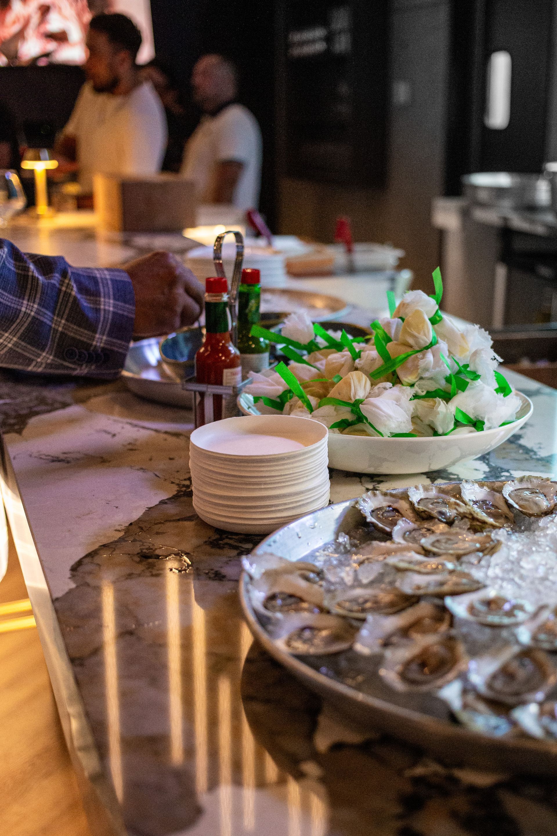 A tray of oysters on ice is on a table in a restaurant.