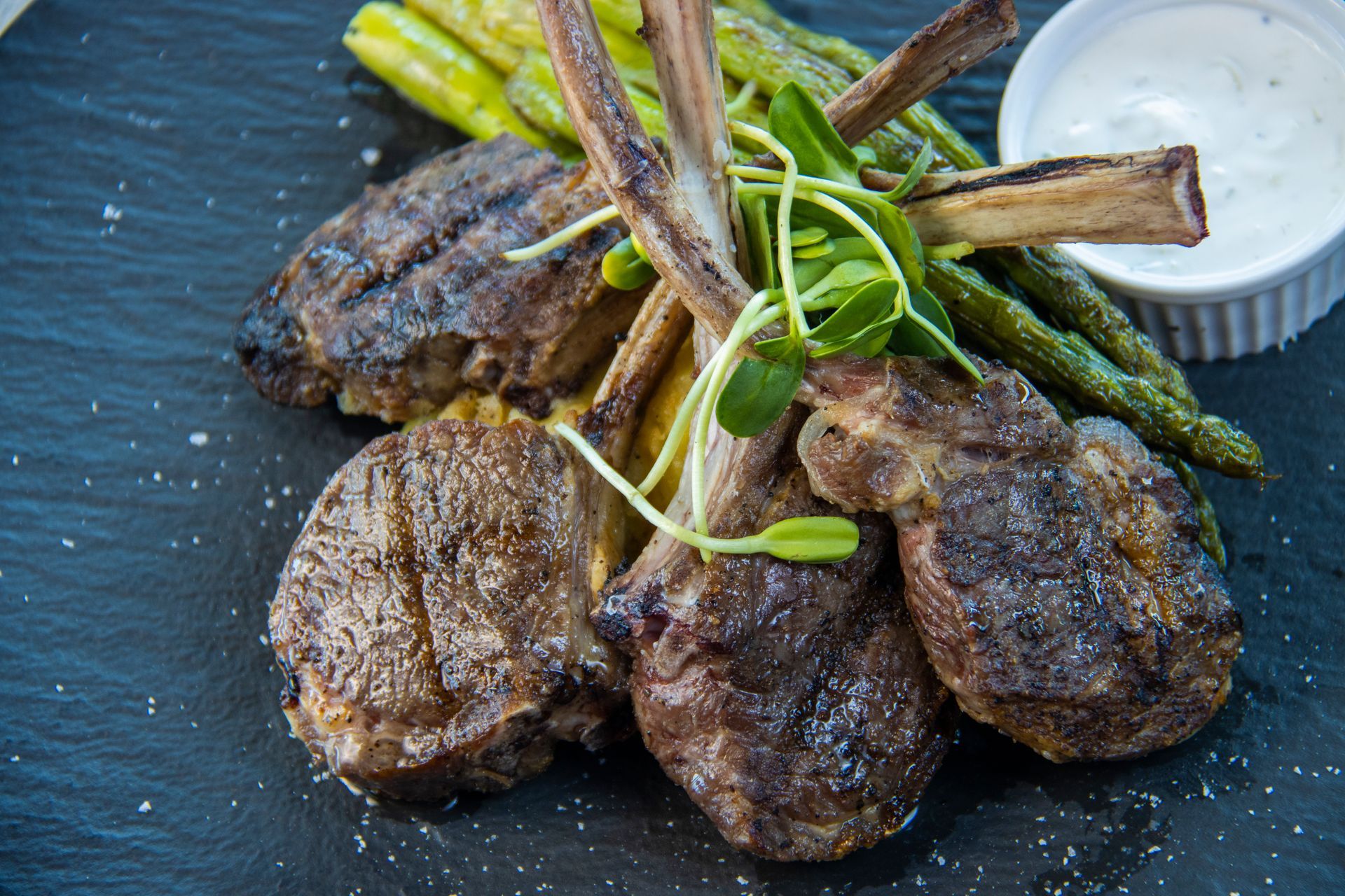 A close up of a plate of lamb chops and asparagus on a table.