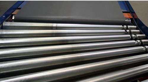 A bunch of metal pipes are stacked on top of each other on a conveyor belt.