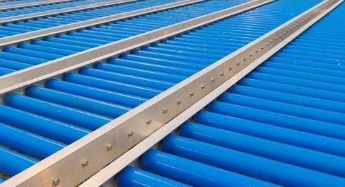 A conveyor belt with blue rollers and a metal railing.