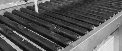A black and white photo of a conveyor belt with rollers on it.