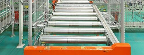 A conveyor belt is going down a staircase in a factory.