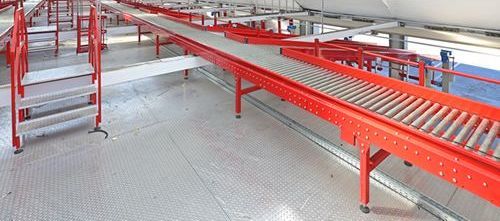 A conveyor belt is going down a warehouse floor.