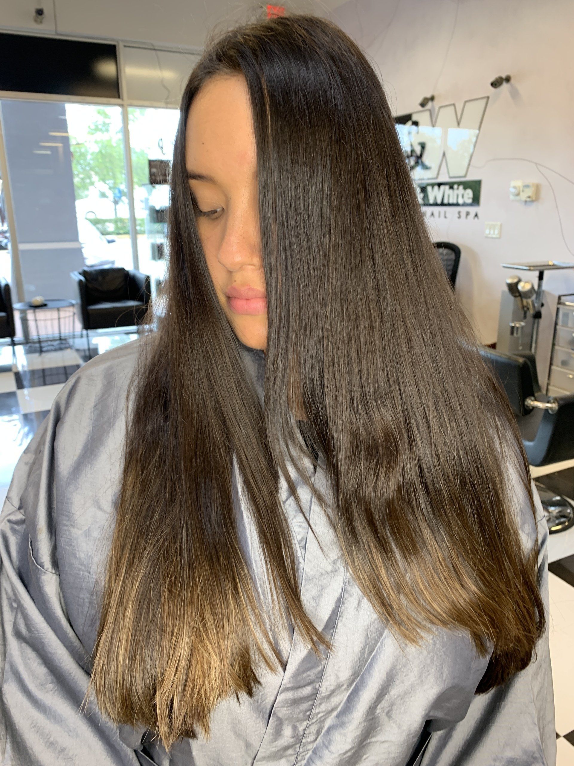 A woman with long hair is getting her hair cut in a salon.