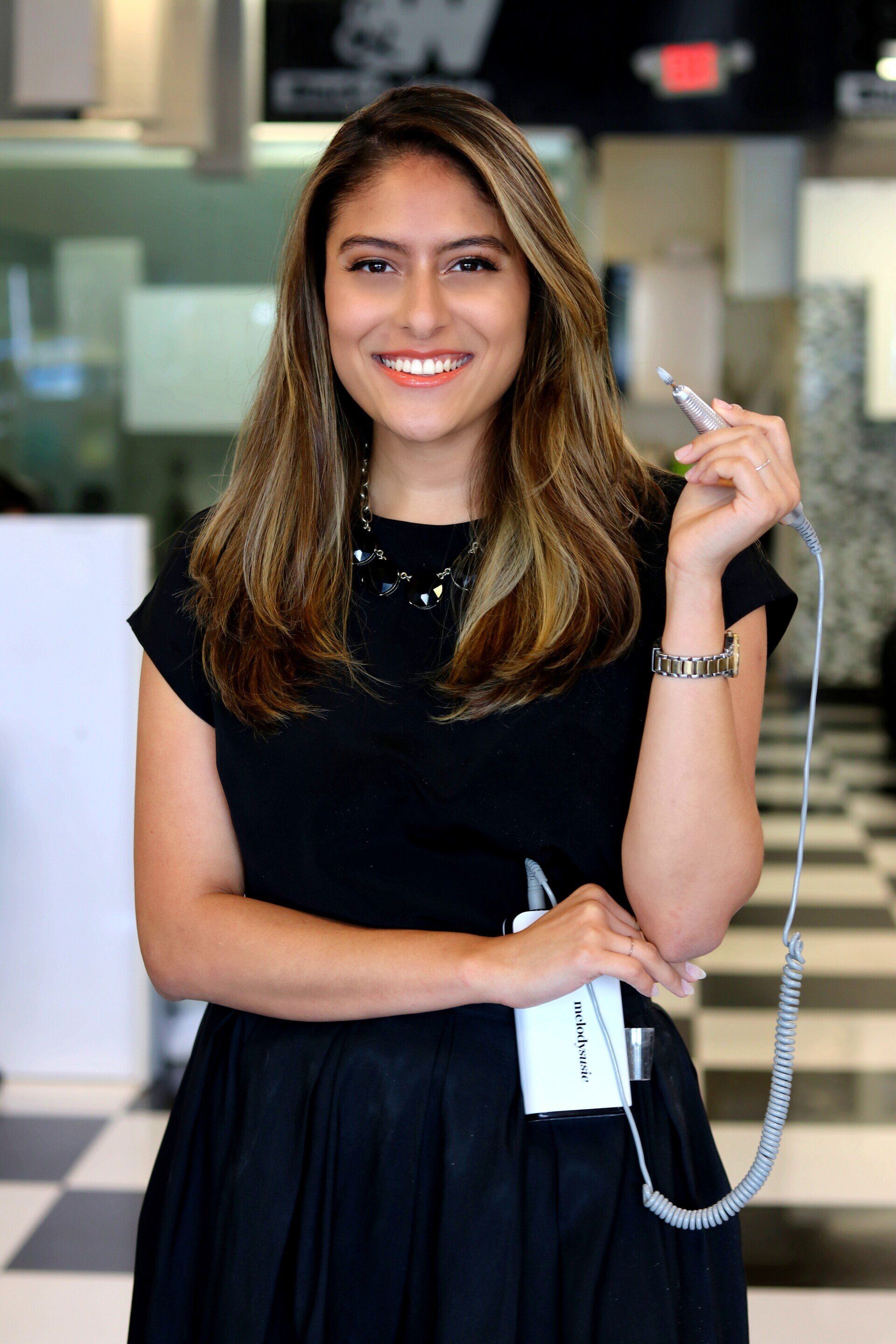 A woman in a black dress is holding a telephone and smiling.