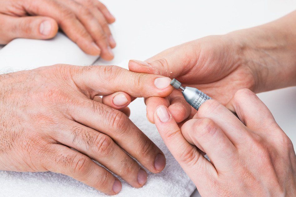 A man is getting his nails done by a woman.