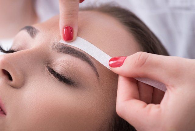 A woman is getting her eyebrows waxed in a beauty salon.