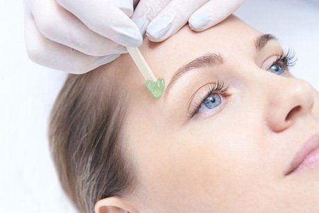 A woman is getting her eyebrows waxed at a beauty salon.