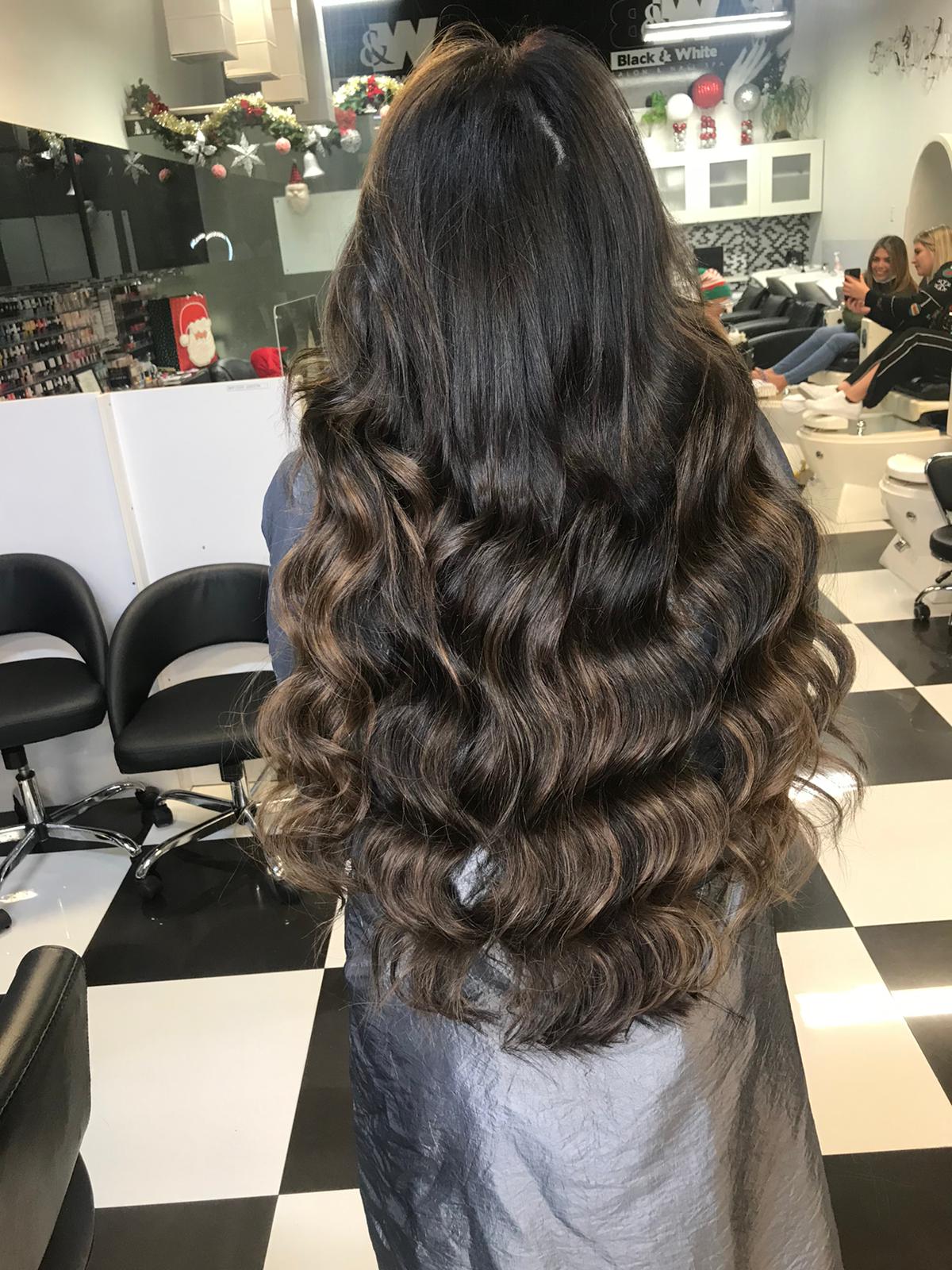 A woman with long hair is standing in a salon.