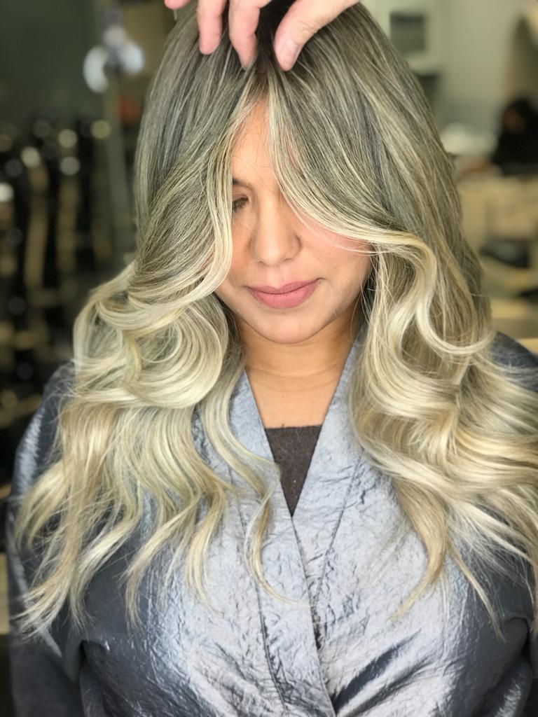 A woman with long blonde hair is getting her hair done in a salon.