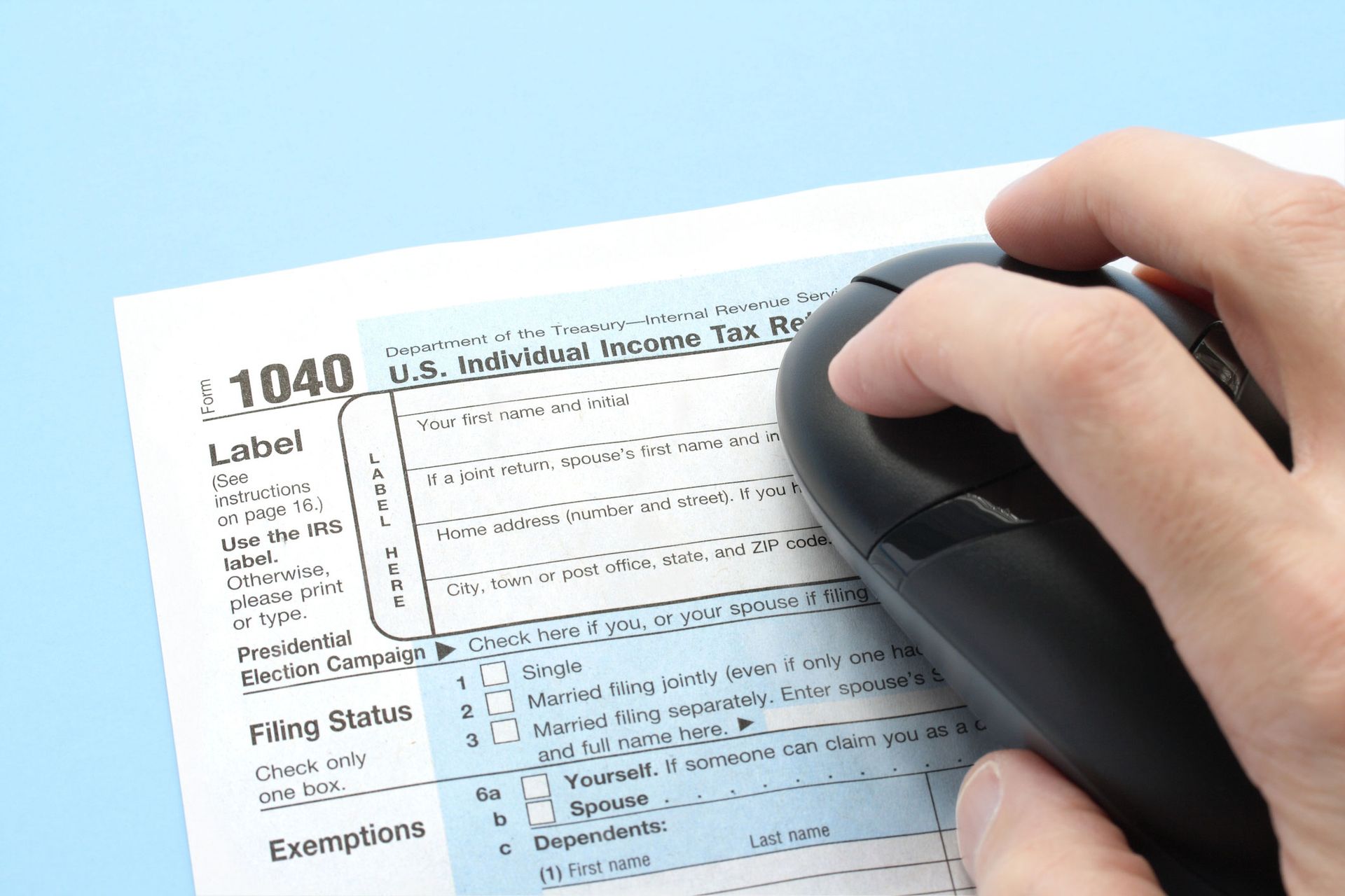 A person is using a computer mouse to fill out a 1040 tax form