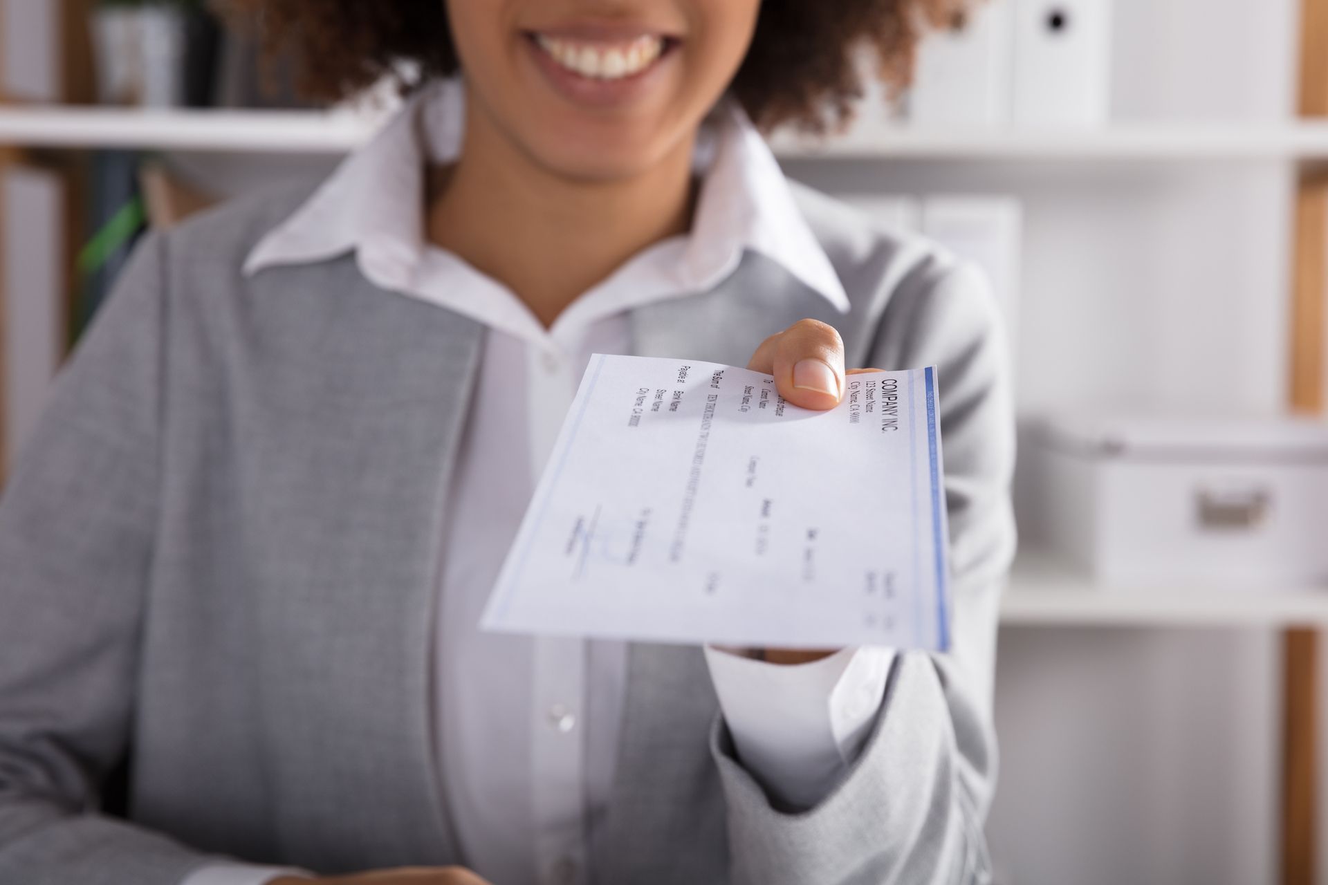 A woman is holding a check in her hand and smiling.