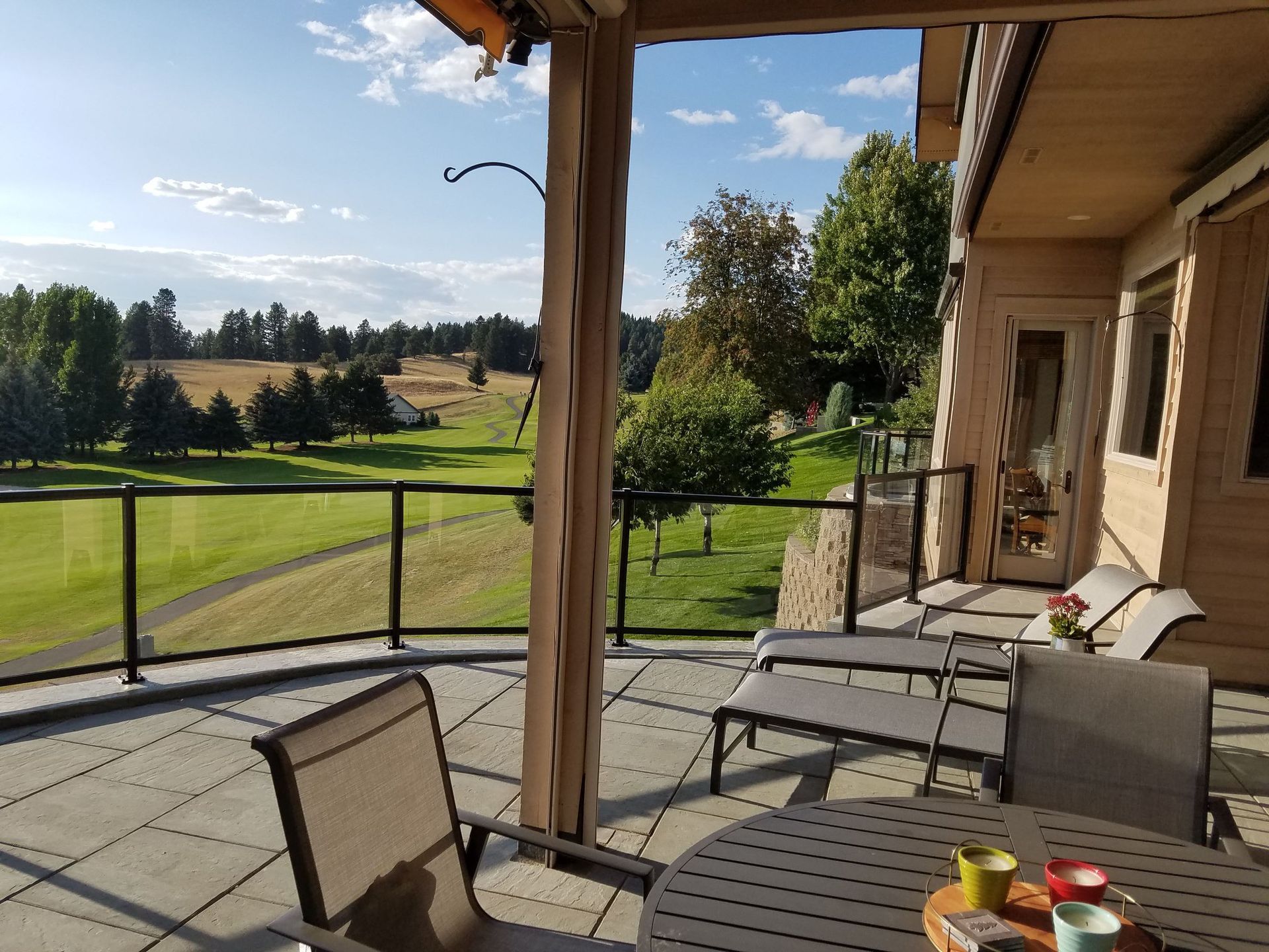 Patio overlooking a green golf course; chairs and table on the deck, sunny day.