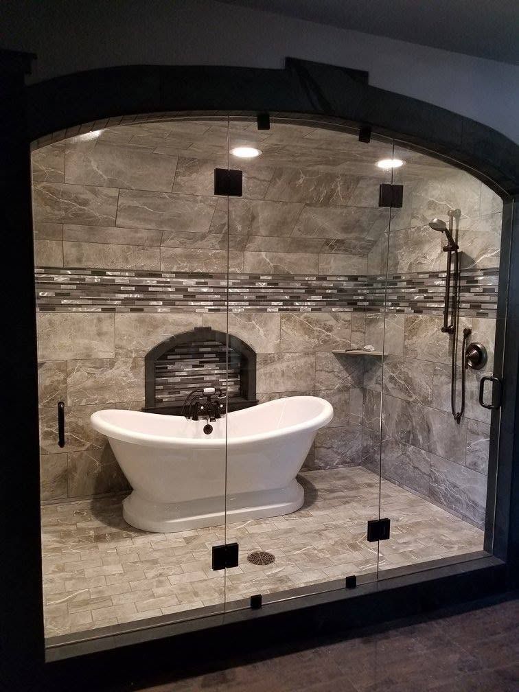 A luxury shower with a freestanding bathtub, stone walls, and glass doors.