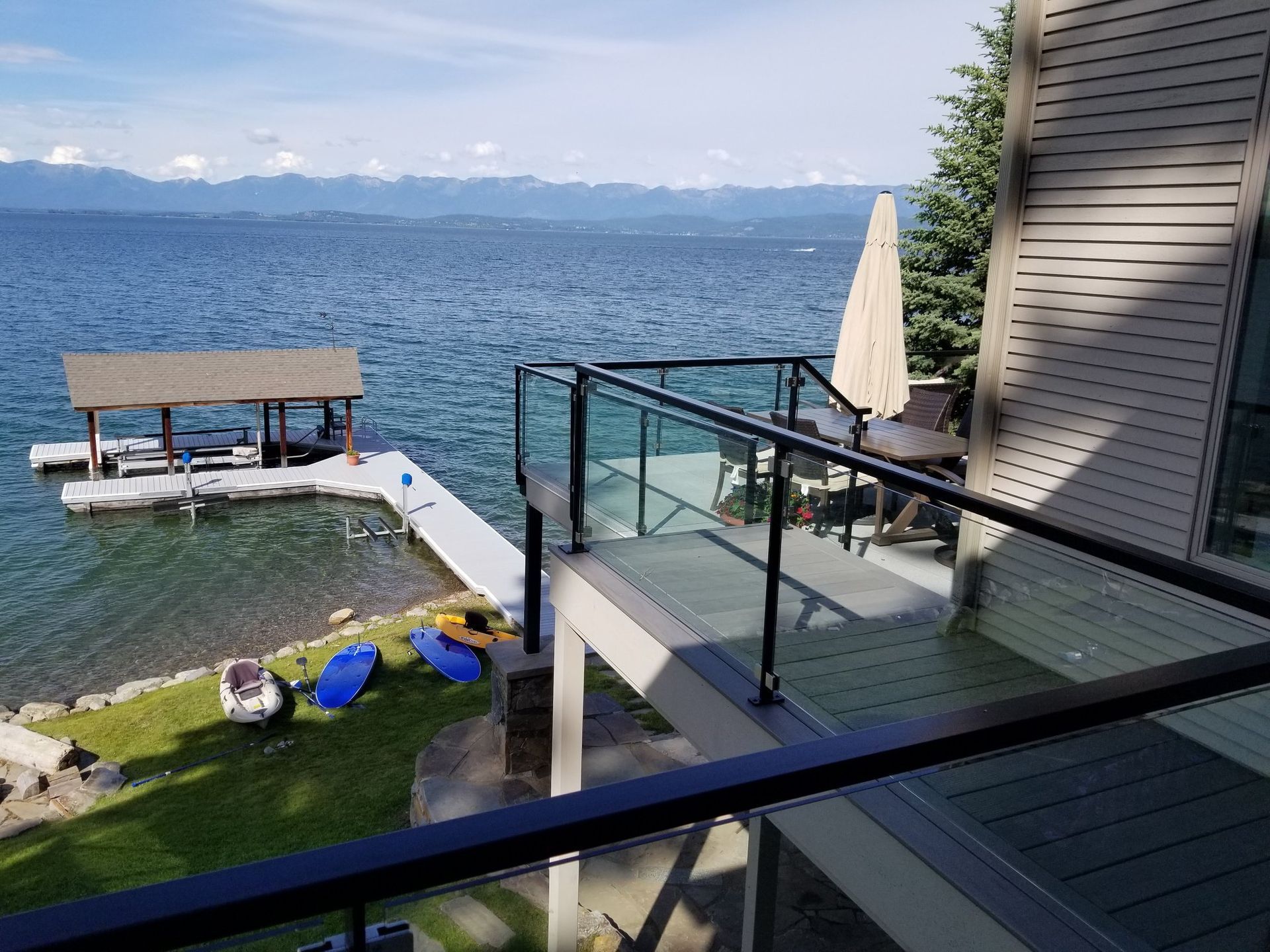 Deck overlooking lake with dock and mountains in the distance.