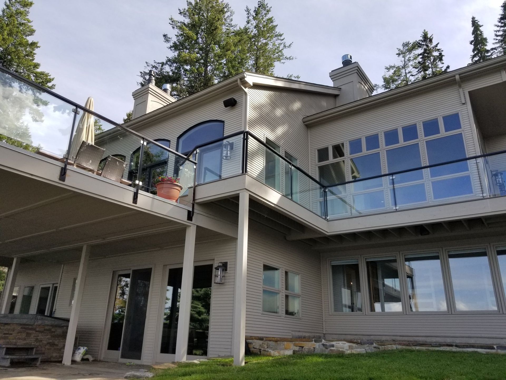 Beige house with glass balconies and large windows; sunny day.