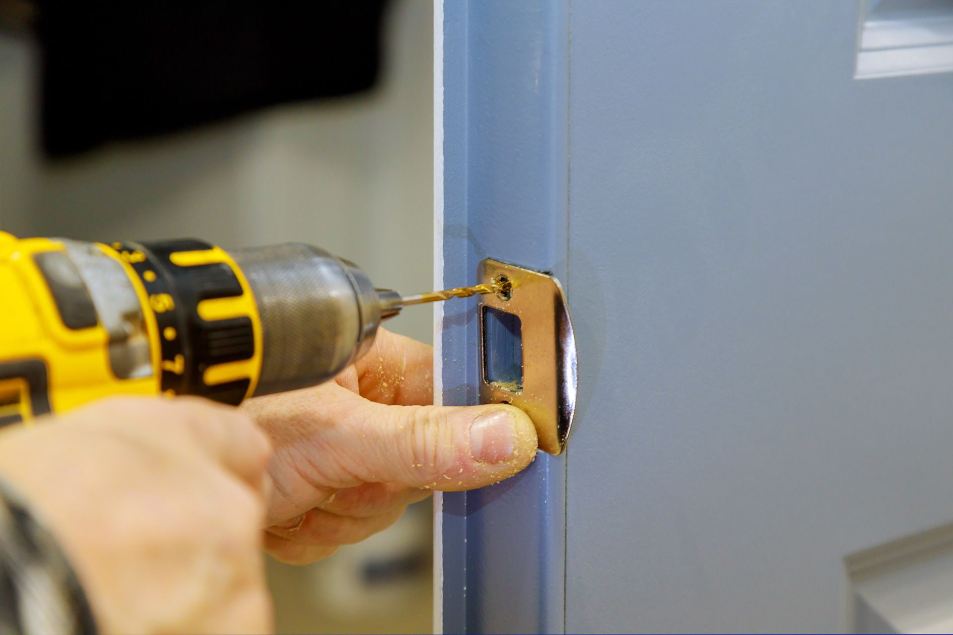 A person is using a drill to drill a hole in a door.