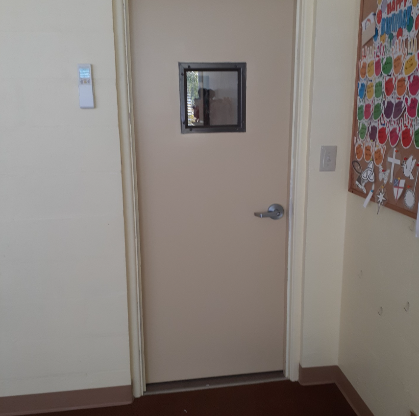 A door with a small window and a bulletin board behind it