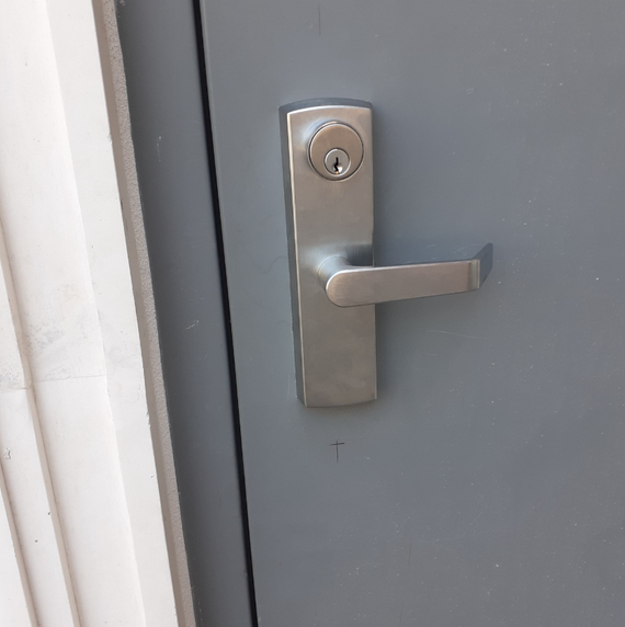 A close up of a door handle on a gray door