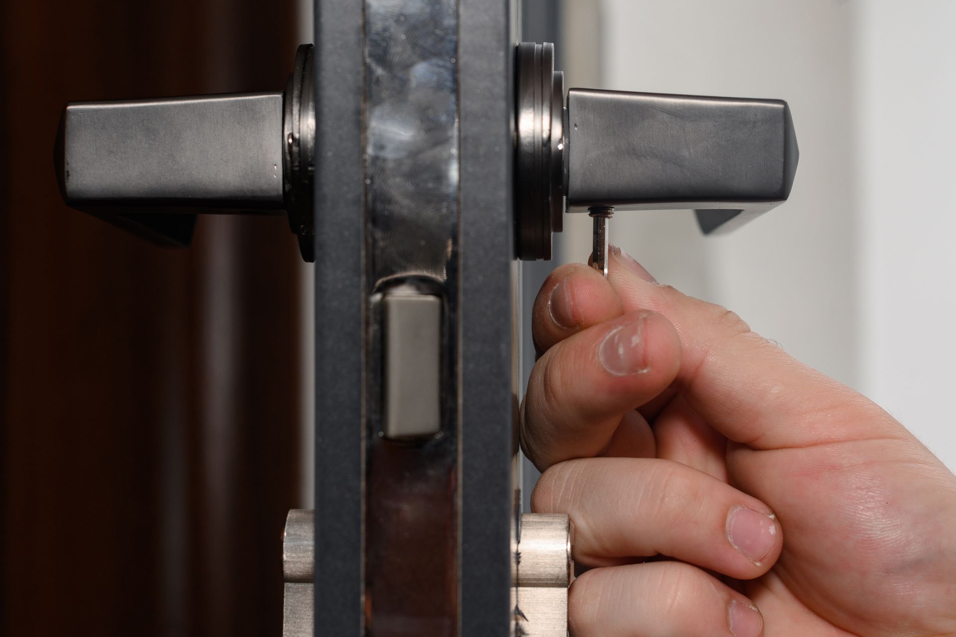 A person is fixing a door lock with a wrench.