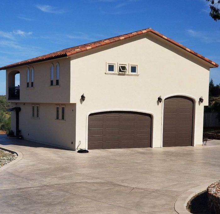 A white house with two garage doors and a balcony