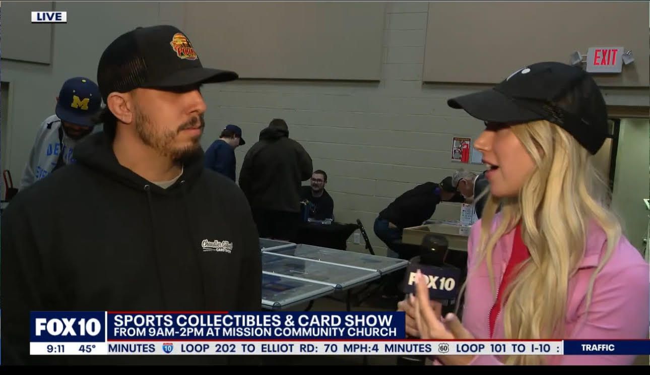 A man and a woman are talking to each other at a sports collectibles and card show.