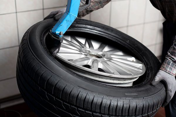 A man is changing a tire on a car with a tire changer.