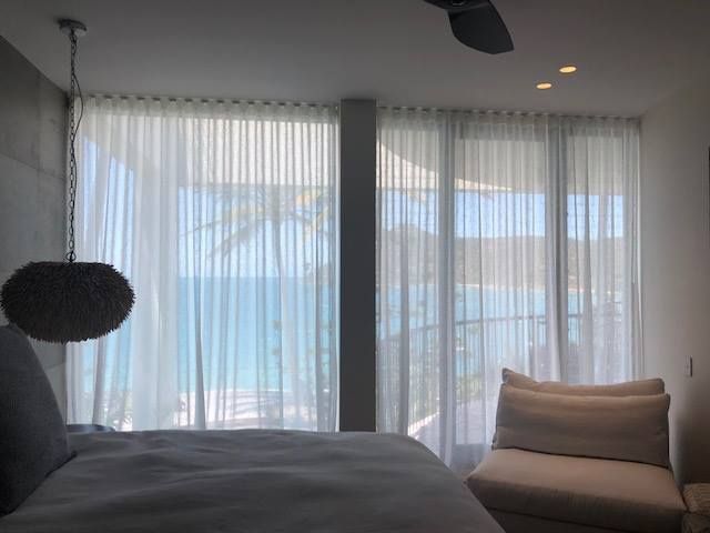 A Bedroom With White Curtains and a View of the Ocean — Whitsunday Vogue Interiors in Cannonvale, QLD