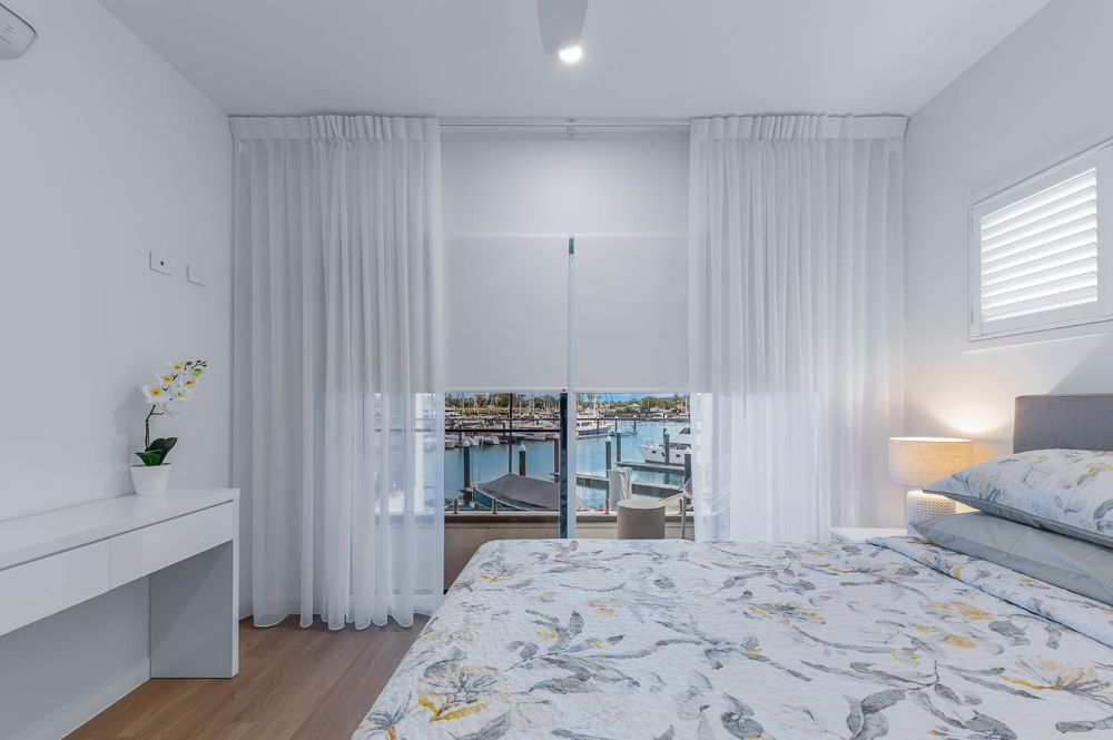 A Bedroom With a Bed, Desk, Window and Curtains — Whitsunday Vogue Interiors in Cannonvale, QLD