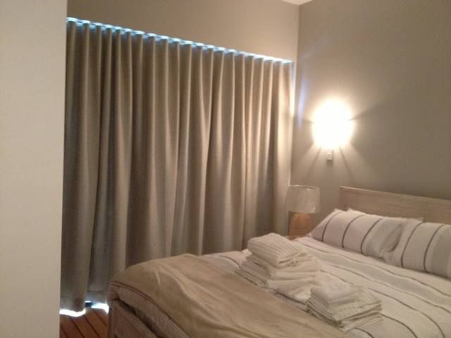 A Bedroom With a Bed and a Window With Curtains — Whitsunday Vogue Interiors in Cannonvale, QLD