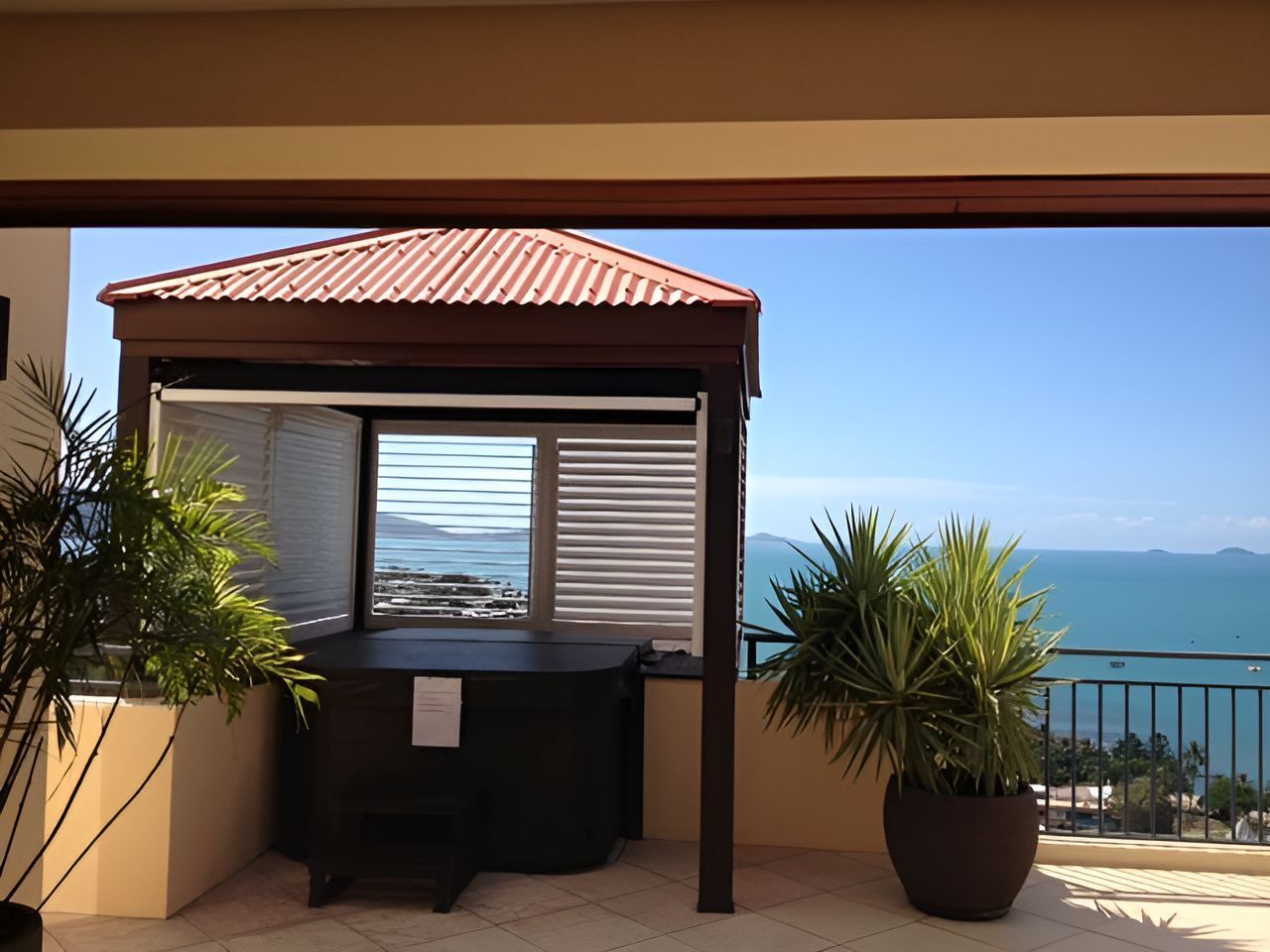 Outdoor Hot Tub With Ocean View, Under a Brown Gazebo, Framed by Potted Plants and a Balcony — Whitsunday Vogue Interiors in Cannonvale, QLD