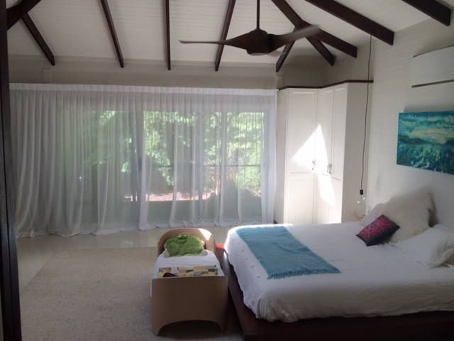 A Bedroom With a Large Bed and a Ceiling Fan — Whitsunday Vogue Interiors in Cannonvale, QLD