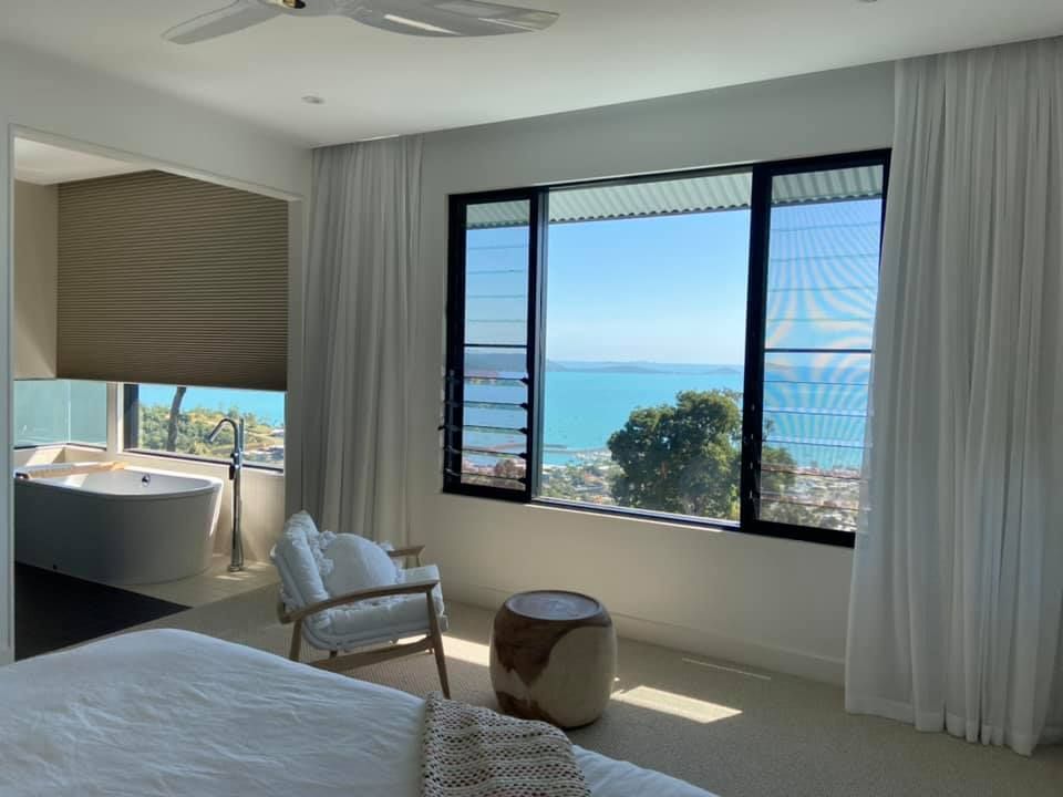 A Bedroom With a Large Window Overlooking the Ocean — Whitsunday Vogue Interiors in Cannonvale, QLD