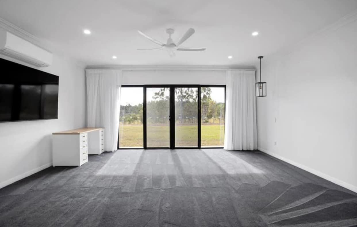 An Empty Living Room With a Sliding Glass Door and a Flat Screen Tv — Whitsunday Vogue Interiors in Cannonvale, QLD