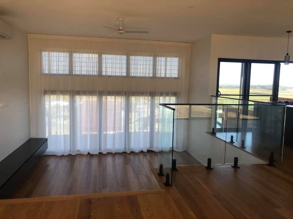 A Living Room With a Staircase Leading Up to a Balcony — Whitsunday Vogue Interiors in Cannonvale, QLD