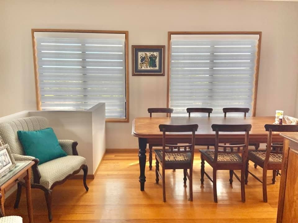 Dining Room With Wooden Table and Chairs, Window Shades, and Decorative Items — Whitsunday Vogue Interiors in Cannonvale, QLD