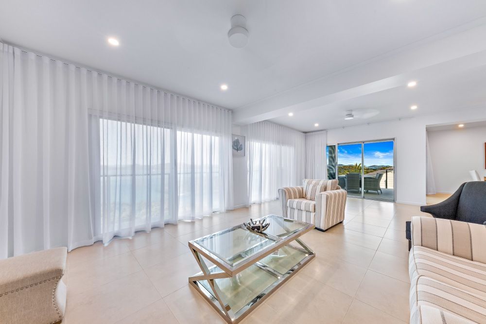 A Living Room With a Couch , Chair , Coffee Table and Sliding Glass Doors — Whitsunday Vogue Interiors in Cannonvale, QLD