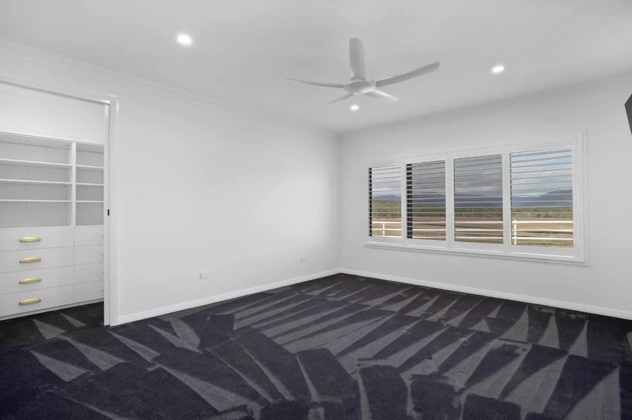 Empty Bedroom With White Walls, Gray Patterned Carpet, Large Window, and Built-in Closet — Whitsunday Vogue Interiors in Cannonvale, QLD