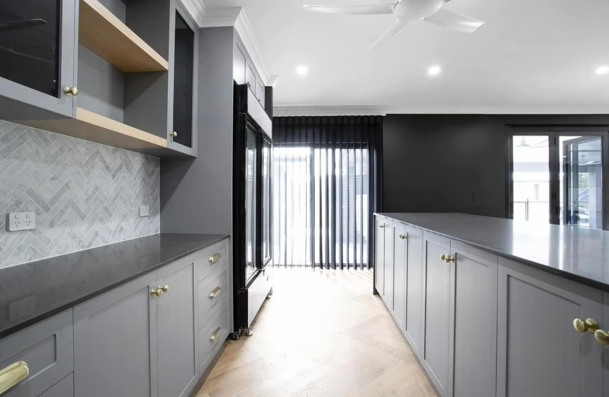 Modern Kitchen With Gray Cabinets, Island, and Backsplash, Gold Hardware, Dark Wall, and Natural Light — Whitsunday Vogue Interiors in Cannonvale, QLD