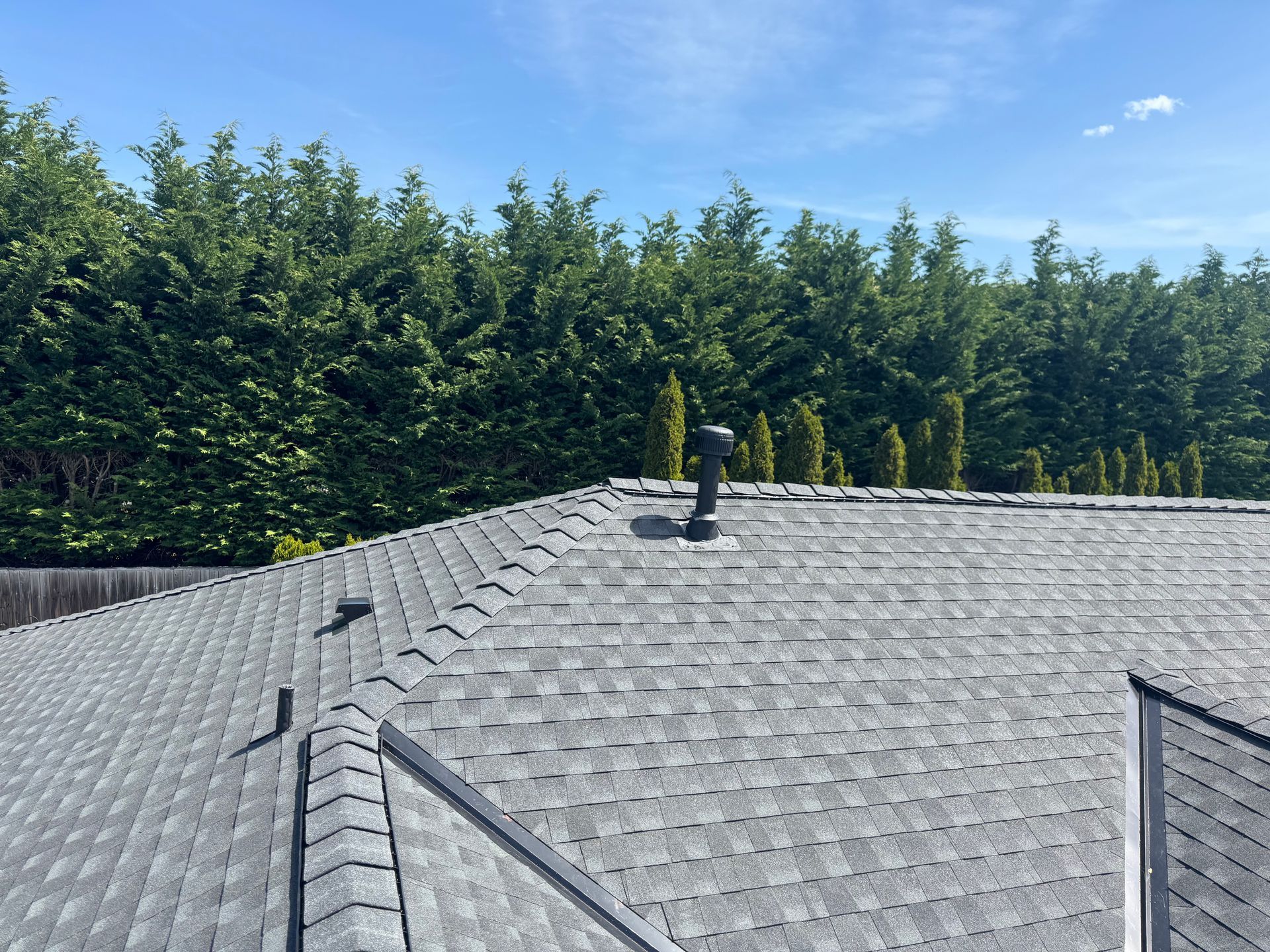 A roof with a chimney on it and trees in the background.
