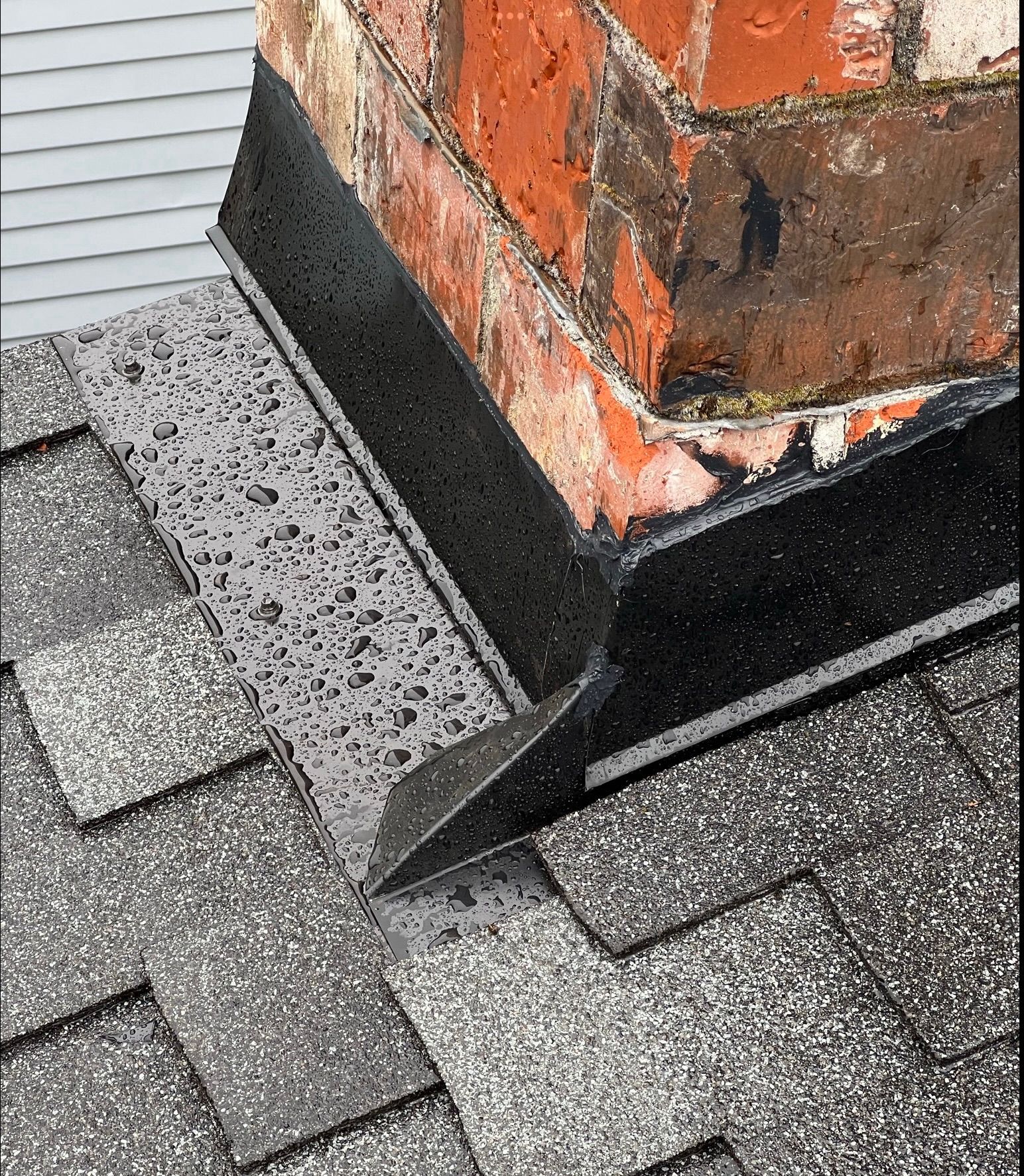 A brick chimney is sitting on top of a roof.