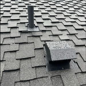 A close up of a roof with shingles and a chimney on it.