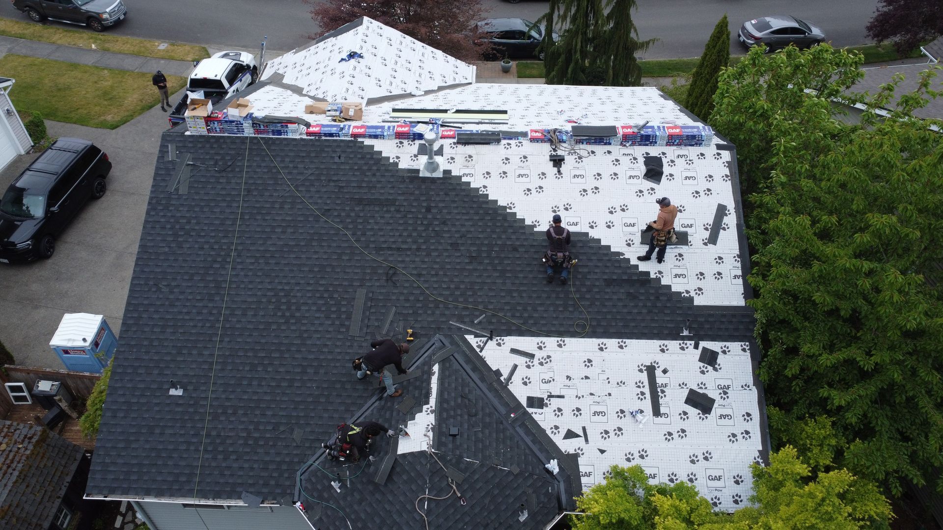 A group of people are working on the roof of a house.