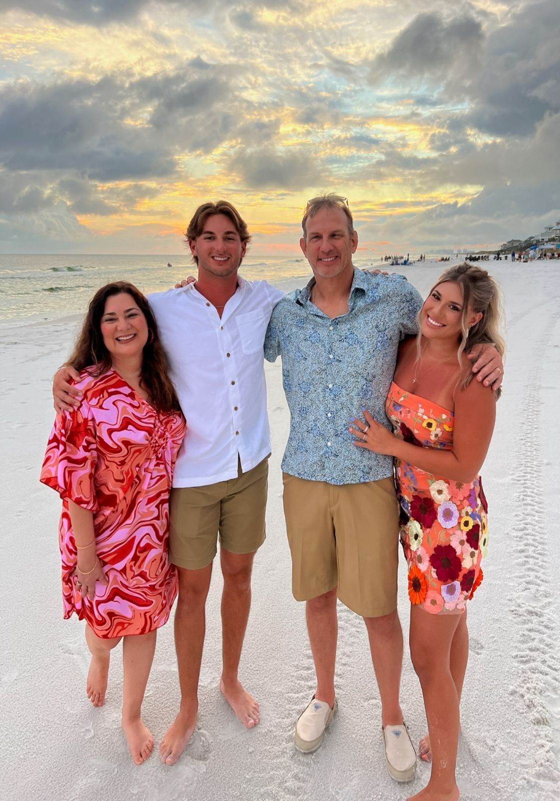 Four people smiling on a beach at sunset. 