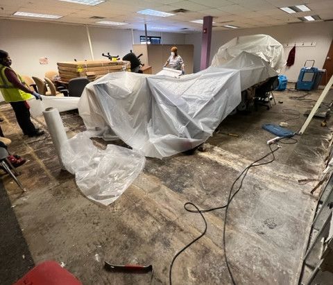 A room with a motorcycle wrapped in plastic and a hammer.