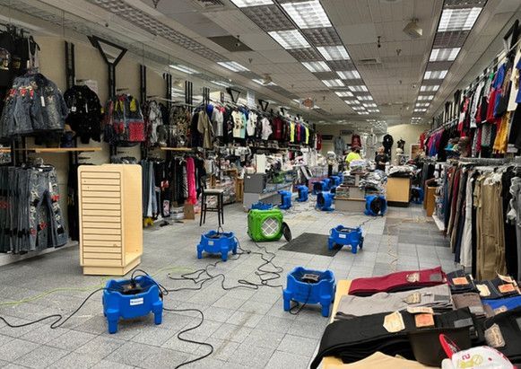 A large clothing store with a lot of clothes on display and a lot of blue fans on the floor.