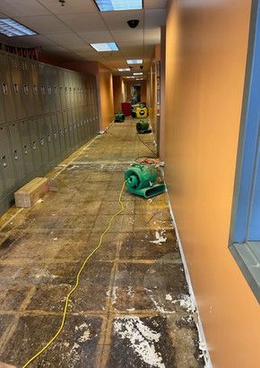 A hallway with a lot of lockers and a green machine on the floor.