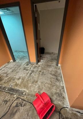 A red air conditioner is sitting on the floor of a room.